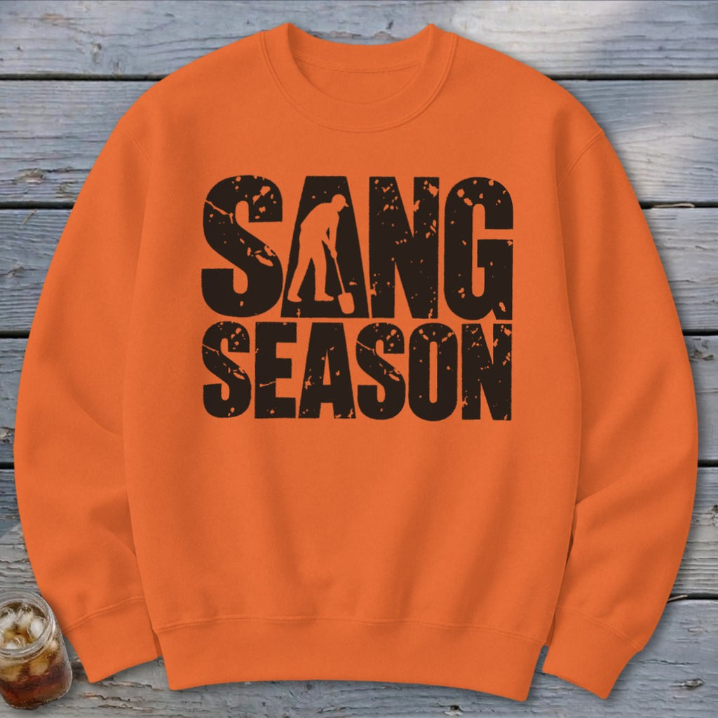 Bright orange crewneck sweatshirt featuring black distressed text that reads SANG SEASON with a silhouetted digger.