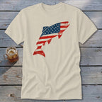 Cream t-shirt featuring a distressed American flag graphic shaped like a leaping fish, laid on wood planks with a glass of iced tea.