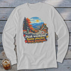 White long-sleeve shirt with autumn mountain road graphic and text: Peak weekend. Same playlist. New overlook.