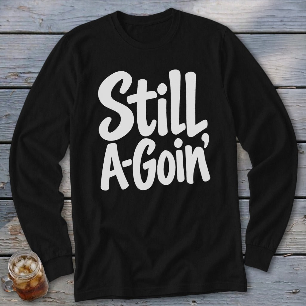 A black long-sleeve t-shirt with white text reading Still A-Goin centered on the chest.