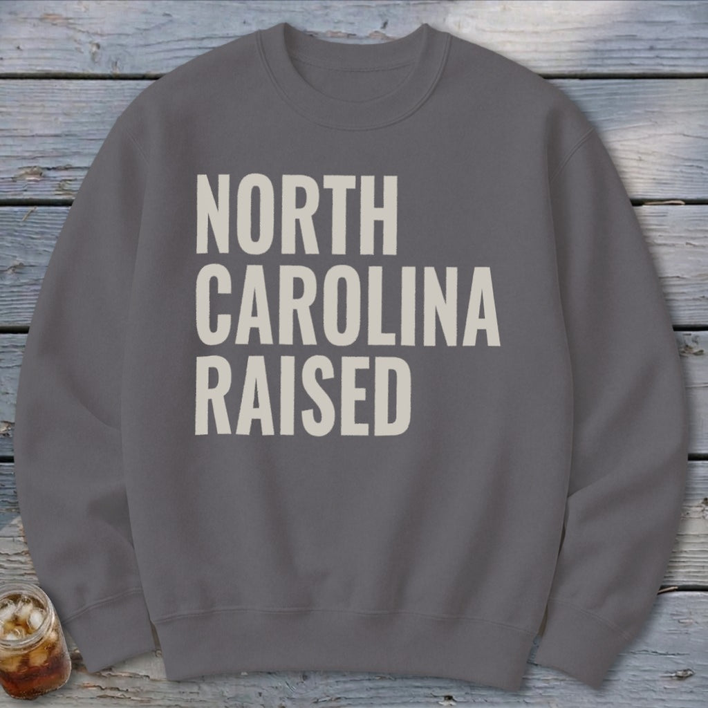 Grey sweatshirt with "NORTH CAROLINA RAISED" text in cream color.