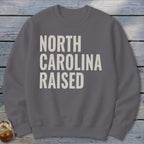 Grey sweatshirt with "NORTH CAROLINA RAISED" text in cream color.