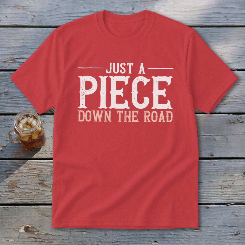 Red t-shirt with "JUST A PIECE DOWN THE ROAD" graphic in white distressed font.