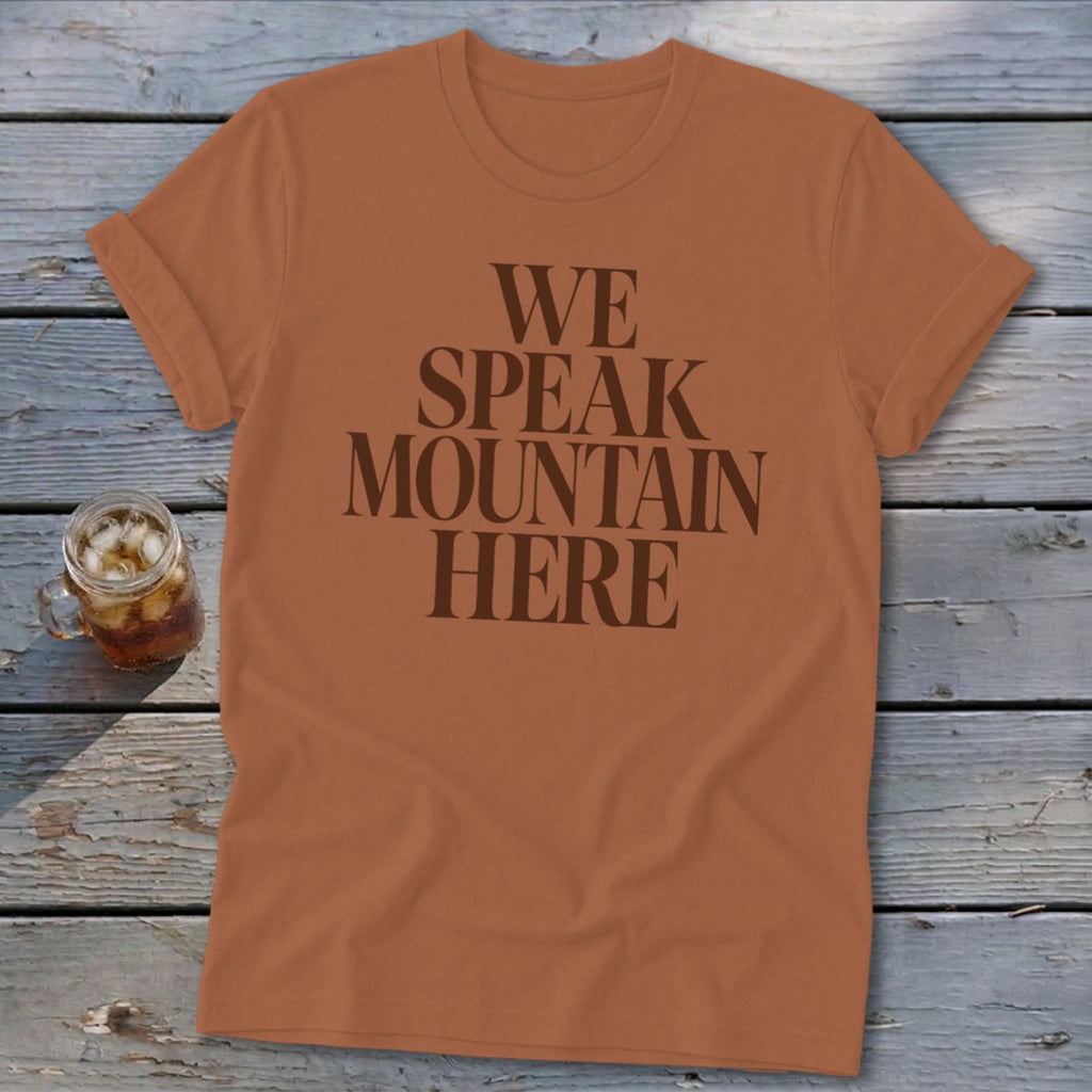 Orange t-shirt with "WE SPEAK MOUNTAIN HERE" text in dark brown.