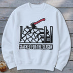 White sweatshirt with a graphic of stacked firewood and an axe, text "STACKED FOR THE SEASON".