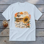 Light blue t-shirt with "Small Town Fall Vibes" graphic featuring a water tower and sunflower.