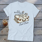 Light blue t-shirt with cream suitcase, flowers, and text "All Roads Lead Back".