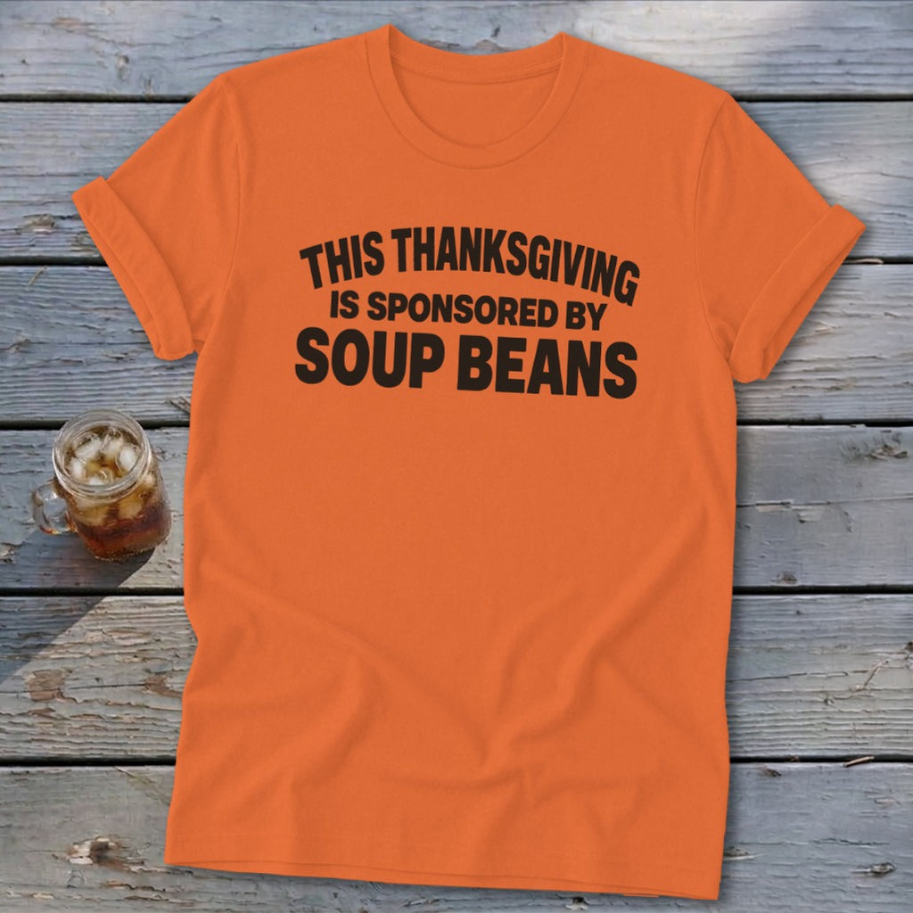 An orange t-shirt featuring the black text, THIS THANKSGIVING IS SPONSORED BY SOUP BEANS.