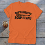 An orange t-shirt featuring the black text, THIS THANKSGIVING IS SPONSORED BY SOUP BEANS.