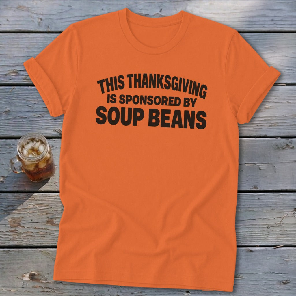 An orange t-shirt featuring the black text, THIS THANKSGIVING IS SPONSORED BY SOUP BEANS.