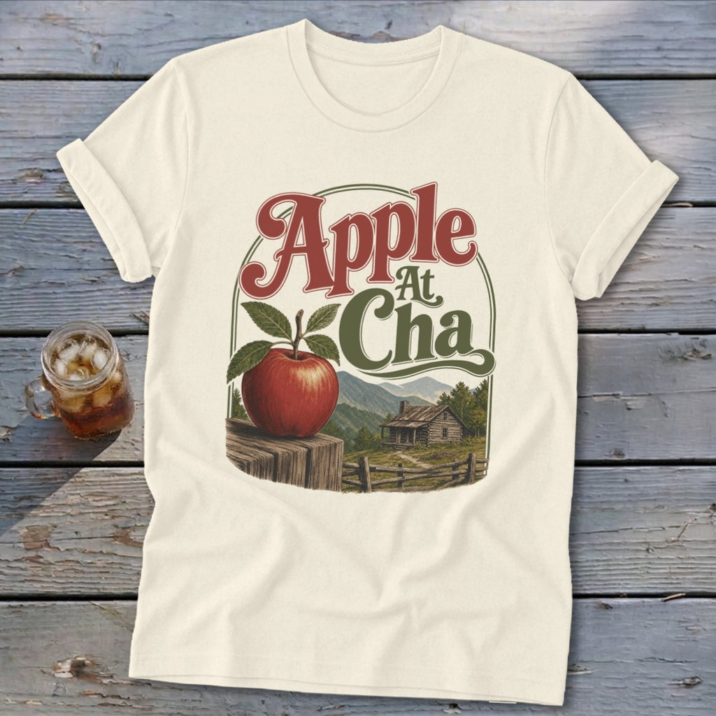 Cream t-shirt featuring a graphic of an apple, a cabin, mountains, and the text Apple At Cha.