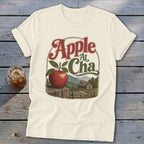 Cream t-shirt featuring a graphic of an apple, a cabin, mountains, and the text Apple At Cha.