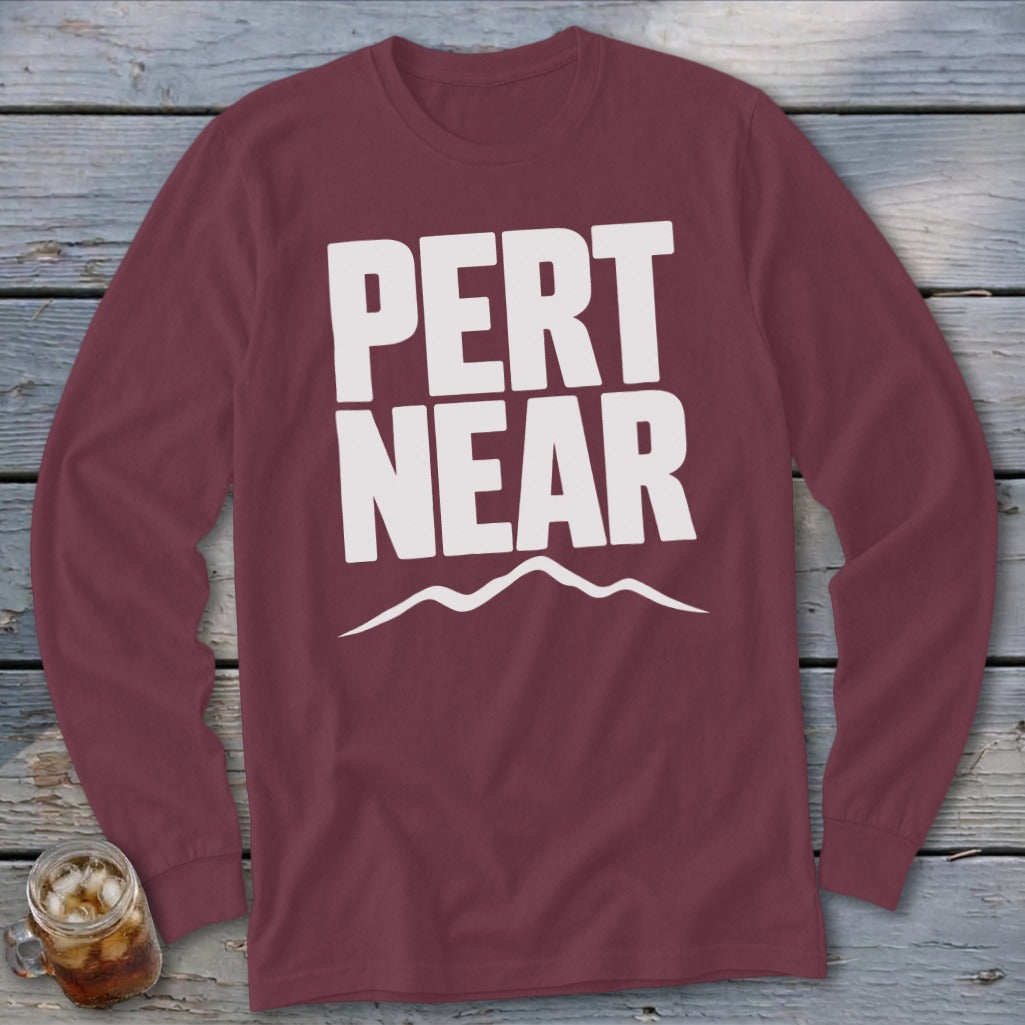 Maroon long-sleeve t-shirt with white text reading PERT NEAR above a mountain range graphic.