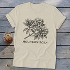 Cream t-shirt with black sketch of rhododendron flowers and "MOUNTAIN BORN" text.