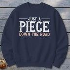 Navy sweatshirt with "JUST A PIECE DOWN THE ROAD" text.