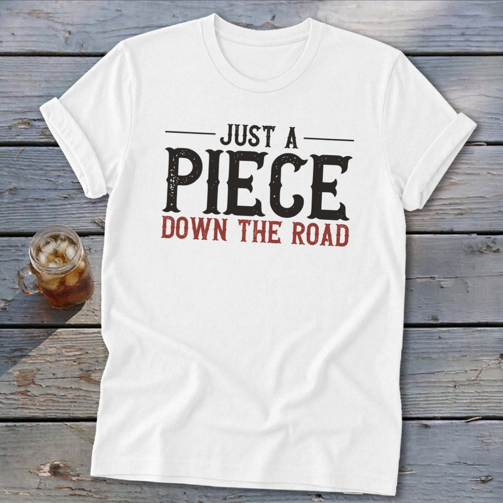 White t-shirt with distressed text "JUST A PIECE DOWN THE ROAD".
