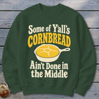 Dark green crewneck sweatshirt featuring a graphic of cornbread in a skillet and text reading Some of Y'all's Cornbread Ain't Done in the Middle.