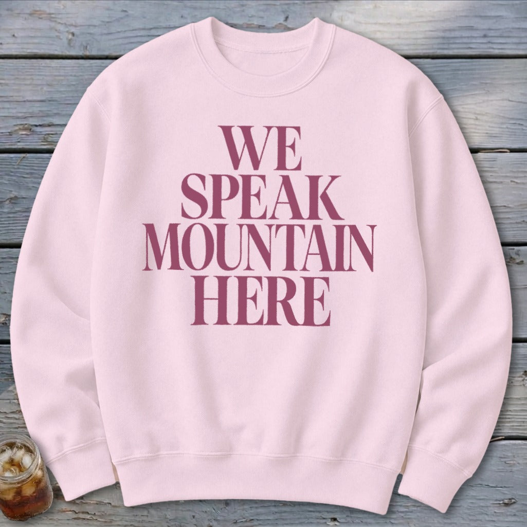 Light pink crewneck sweatshirt with maroon text that reads "WE SPEAK MOUNTAIN HERE".