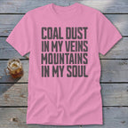 A pink t-shirt with the black text COAL DUST IN MY VEINS MOUNTAINS IN MY SOUL.