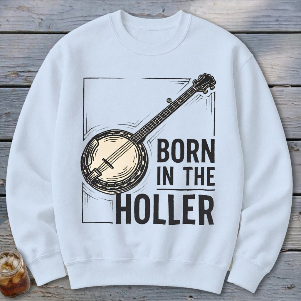 White sweatshirt with a black banjo illustration and text that reads "BORN IN THE HOLLER".