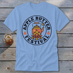Light blue t-shirt with circular "Apple Butter Festival" logo featuring a kettle over a campfire.