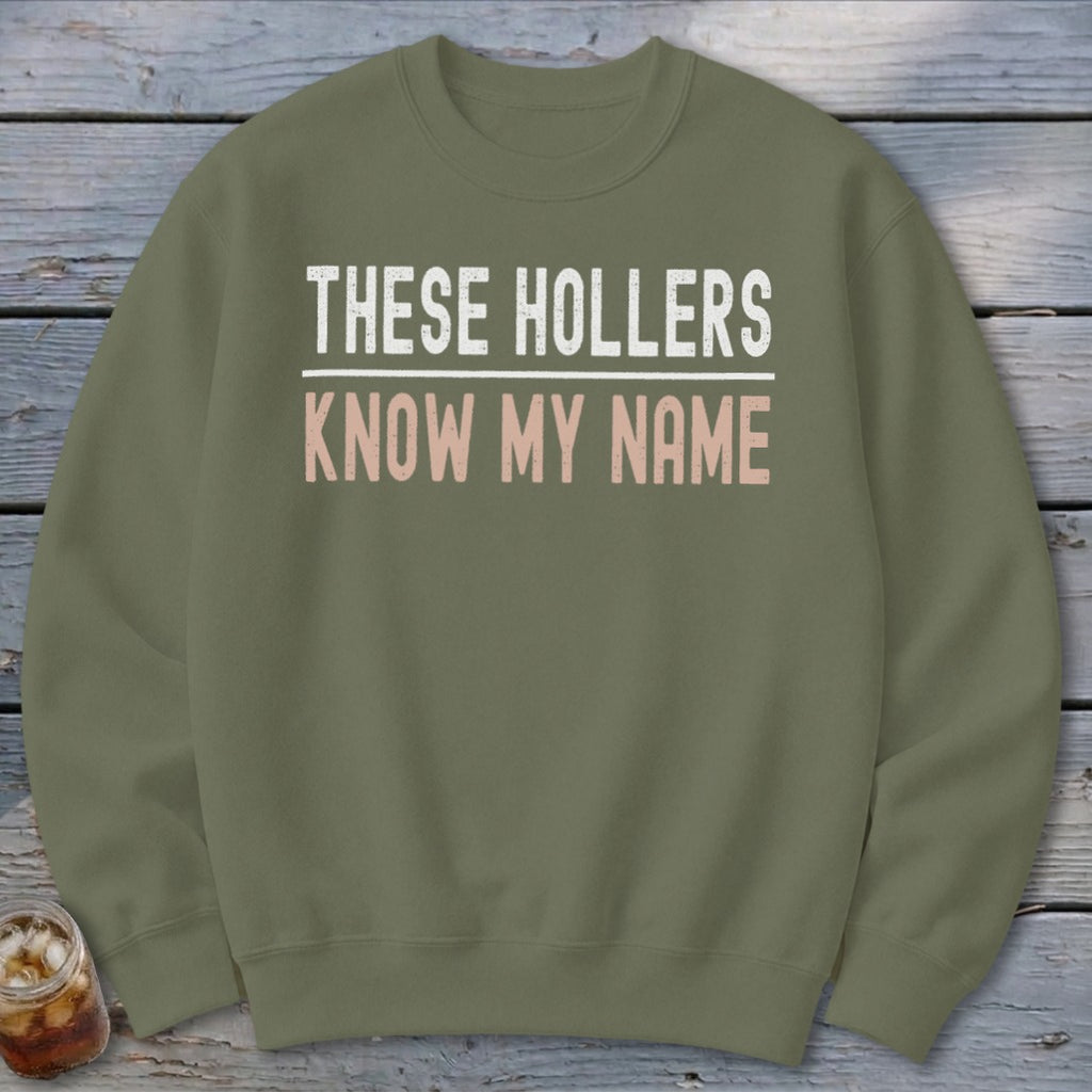 Green sweatshirt with white and pink text reading "THESE HOLLERS KNOW MY NAME."