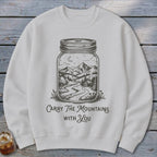 A light gray crewneck sweatshirt featuring a graphic of a jar enclosing a mountain landscape with the text "Carry The Mountains With You."