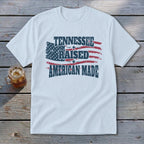 White t-shirt with distressed American flag graphic and text "TENNESSEE RAISED AMERICAN MADE".