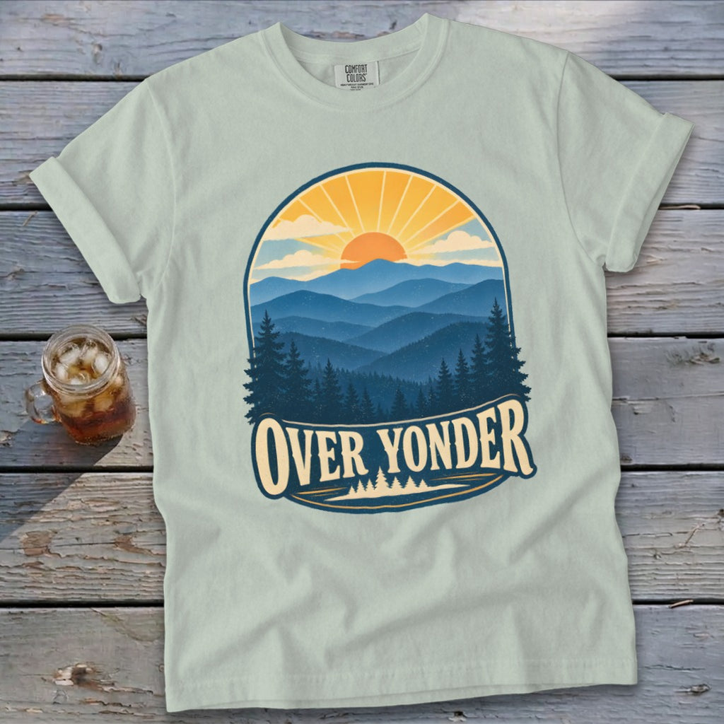 Light green t-shirt with a vintage nature graphic depicting mountains, a sunrise, and text reading OVER YONDER.