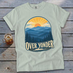 Light green t-shirt with a vintage nature graphic depicting mountains, a sunrise, and text reading OVER YONDER.