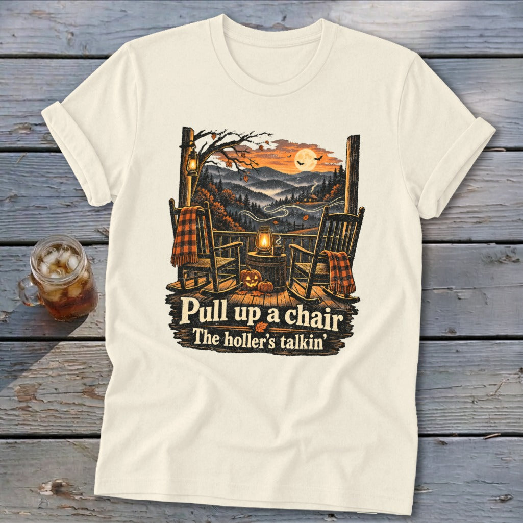 T-shirt graphic with rocking chairs on a porch overlooking a fall mountain scene with text "Pull up a chair The holler's talkin'".