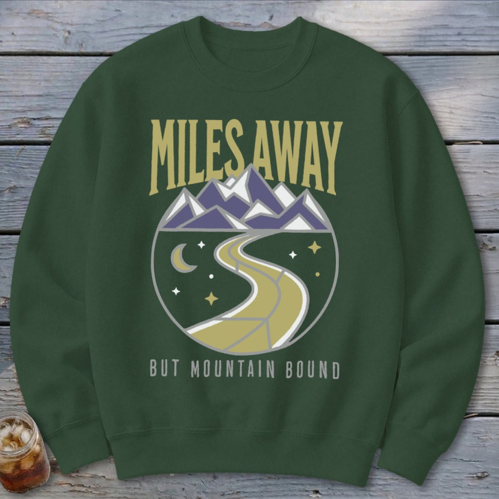 Green sweatshirt with "Miles Away But Mountain Bound" text and mountain, road, moon, and star graphic.