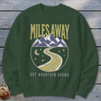 Green sweatshirt with "Miles Away But Mountain Bound" text and mountain, road, moon, and star graphic.