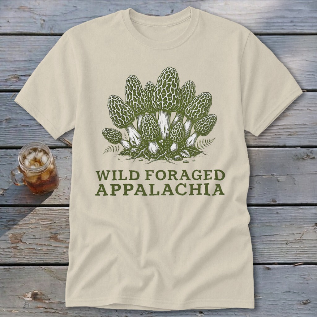 Light-colored t-shirt with a green illustration of morel mushrooms and text "WILD FORAGED APPALACHIA".