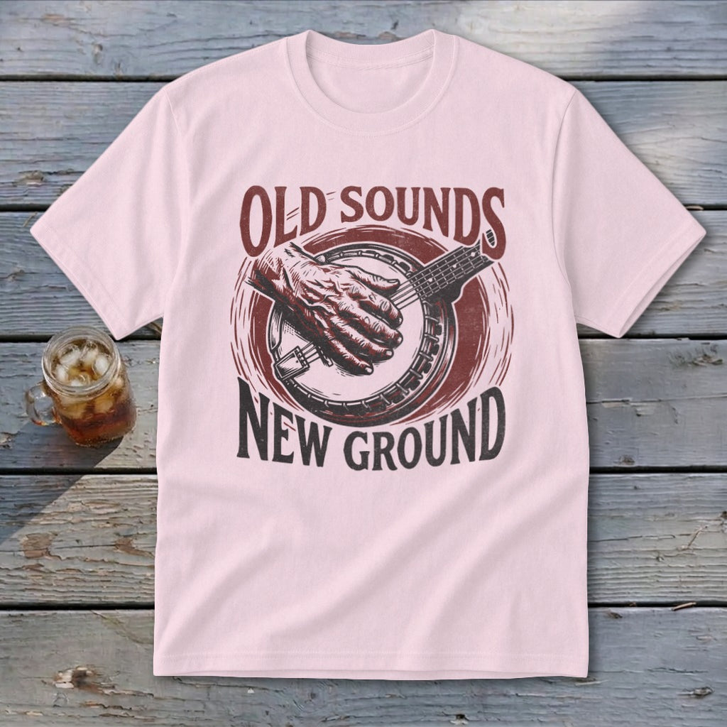 Light pink t-shirt featuring a distressed red graphic of a hand playing a banjo with the text Old Sounds New Ground.