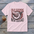 Light pink t-shirt featuring a distressed red graphic of a hand playing a banjo with the text Old Sounds New Ground.