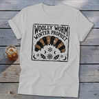 A light gray crewneck t-shirt featuring a black and brown woolly worm graphic with text that reads Woolly Worm Winter Prophet.