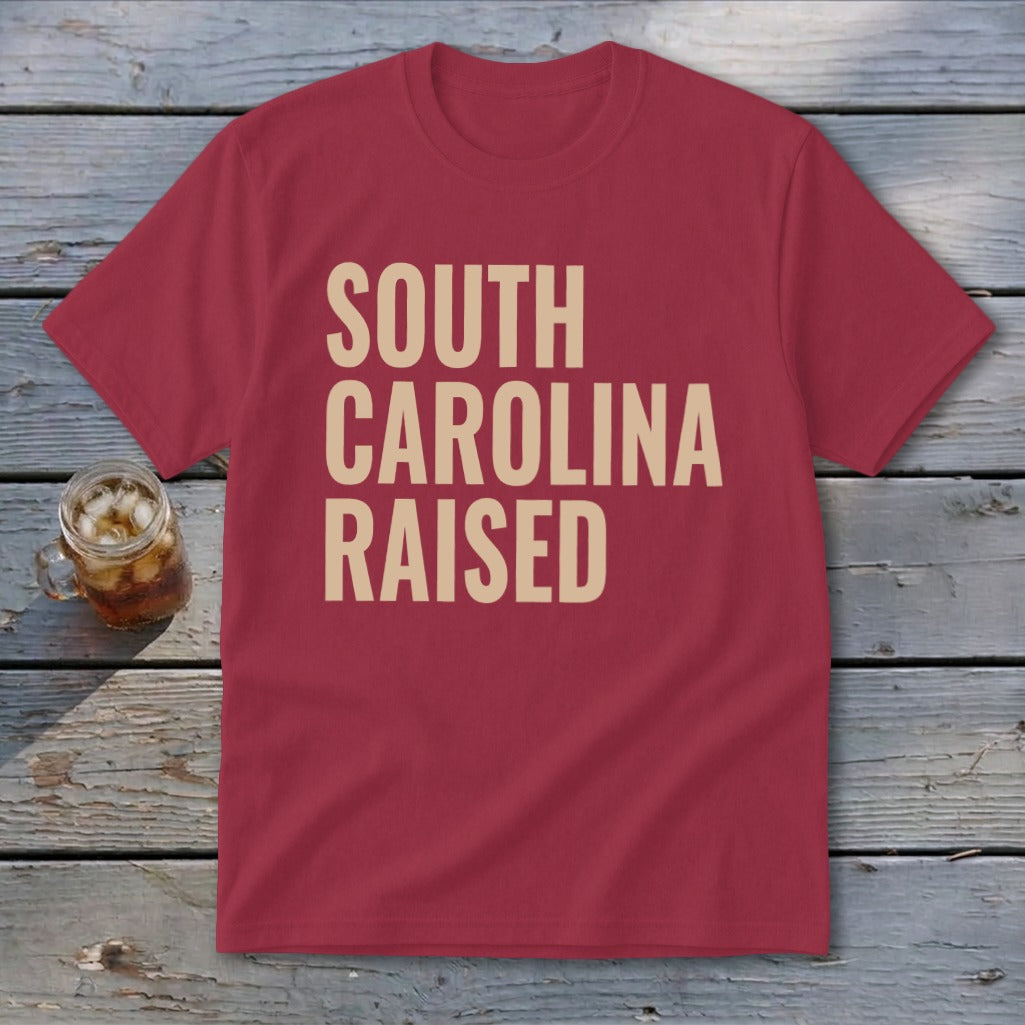Maroon t-shirt with tan text that says "SOUTH CAROLINA RAISED."