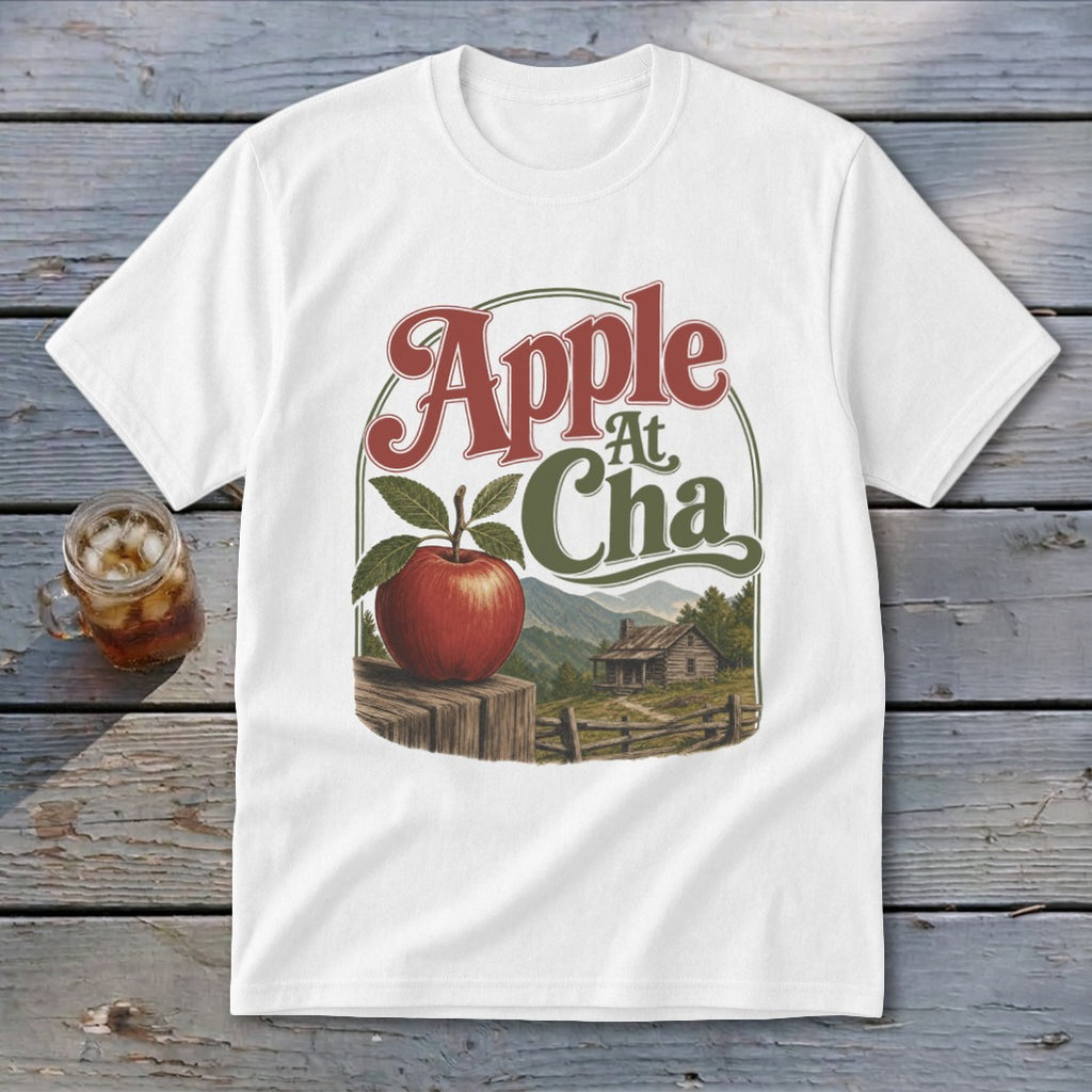 A white short-sleeved t-shirt features a graphic with the text Apple At Cha above a landscape illustration.