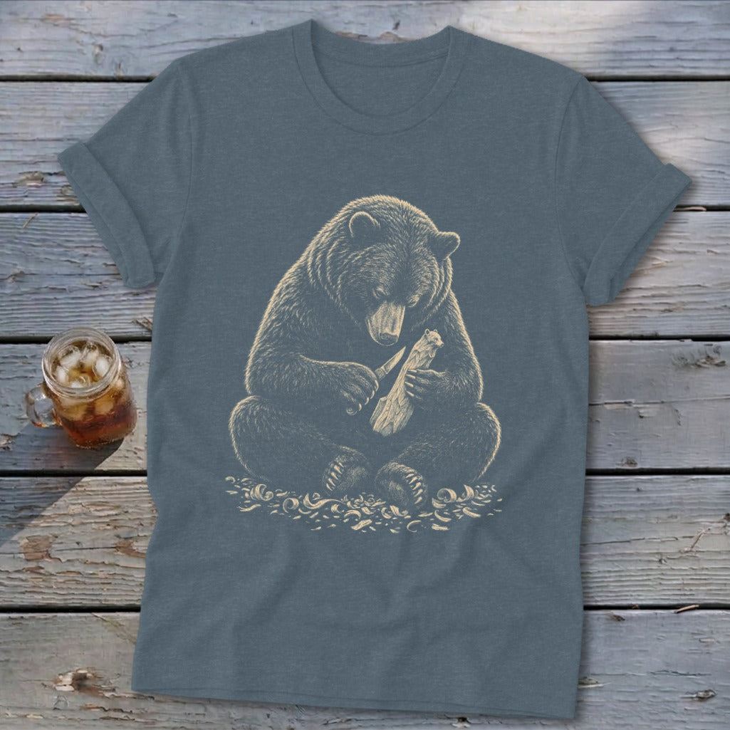 Bear carving a piece of wood on a dark blue t-shirt.