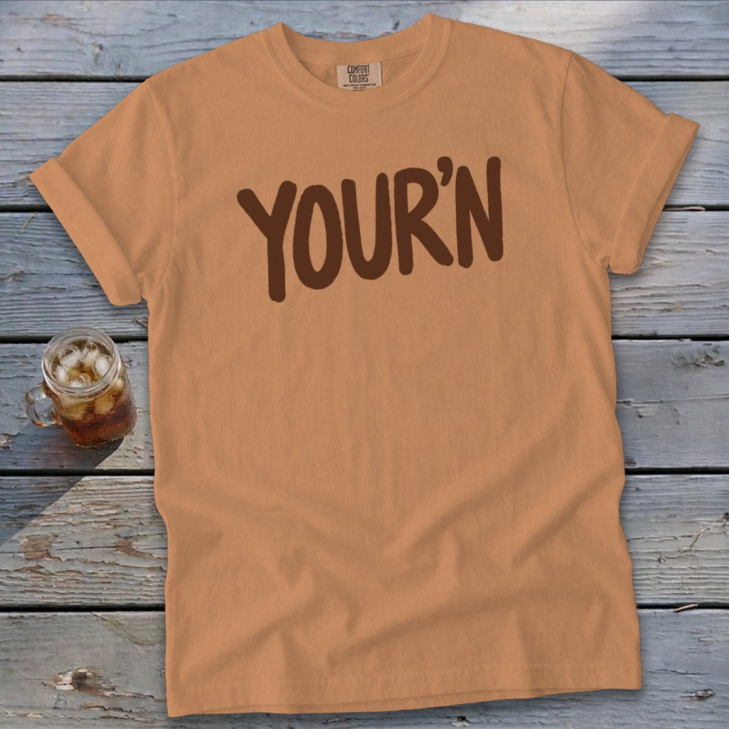 Orange t-shirt with brown "YOUR'N" text and a glass of iced tea.