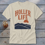 Cream-colored t-shirt featuring a retro graphic of mountains and the text "HOLLER LIFE" in orange.