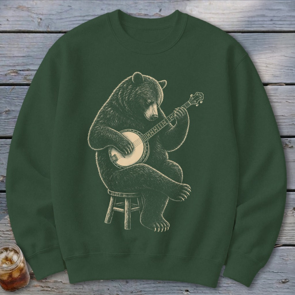 Bear playing banjo while sitting on a stool on a dark green sweatshirt.