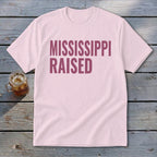 Light pink t-shirt with maroon text that says "MISSISSIPPI RAISED".