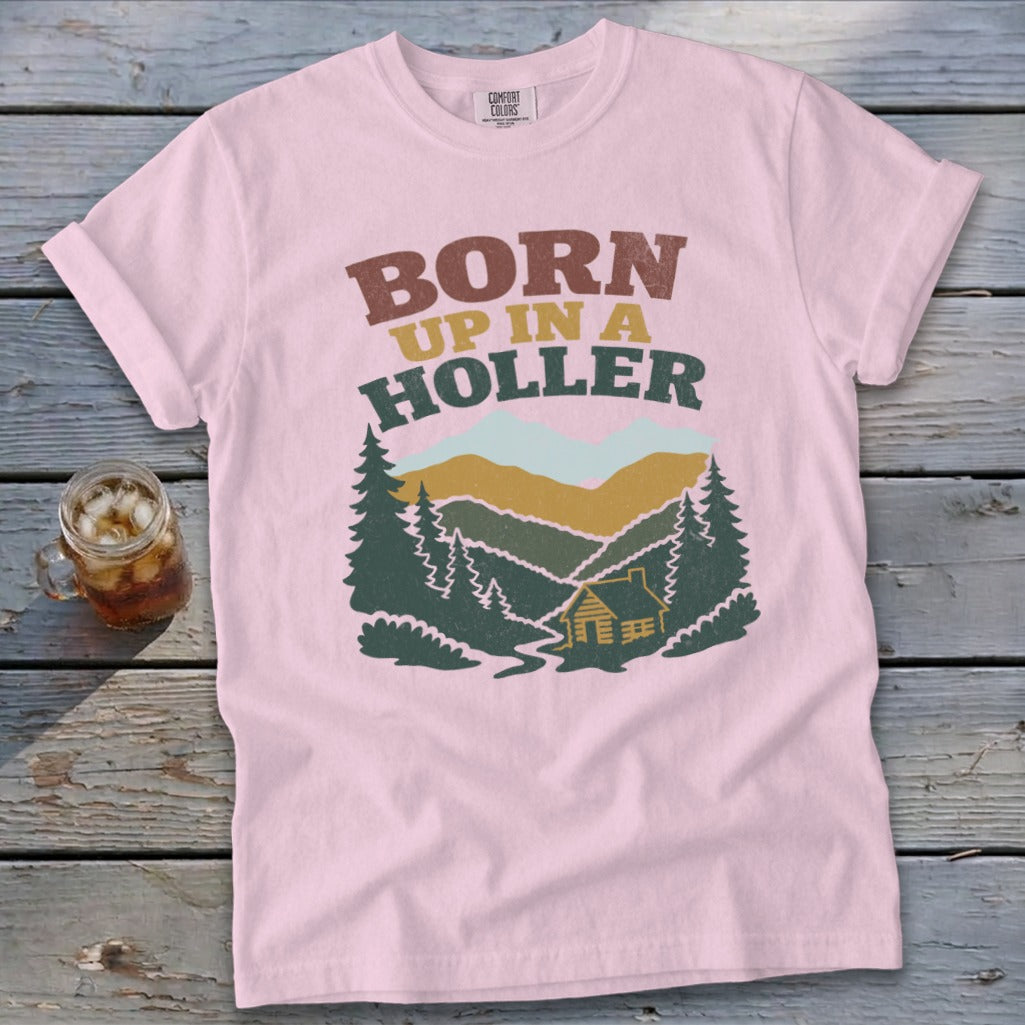Pink t-shirt with "BORN UP IN A HOLLER" text and mountain landscape graphic.