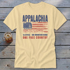 A cream-colored t-shirt featuring a distressed American flag graphic with the text Appalachia, 13 states, one mountain range, one free country.