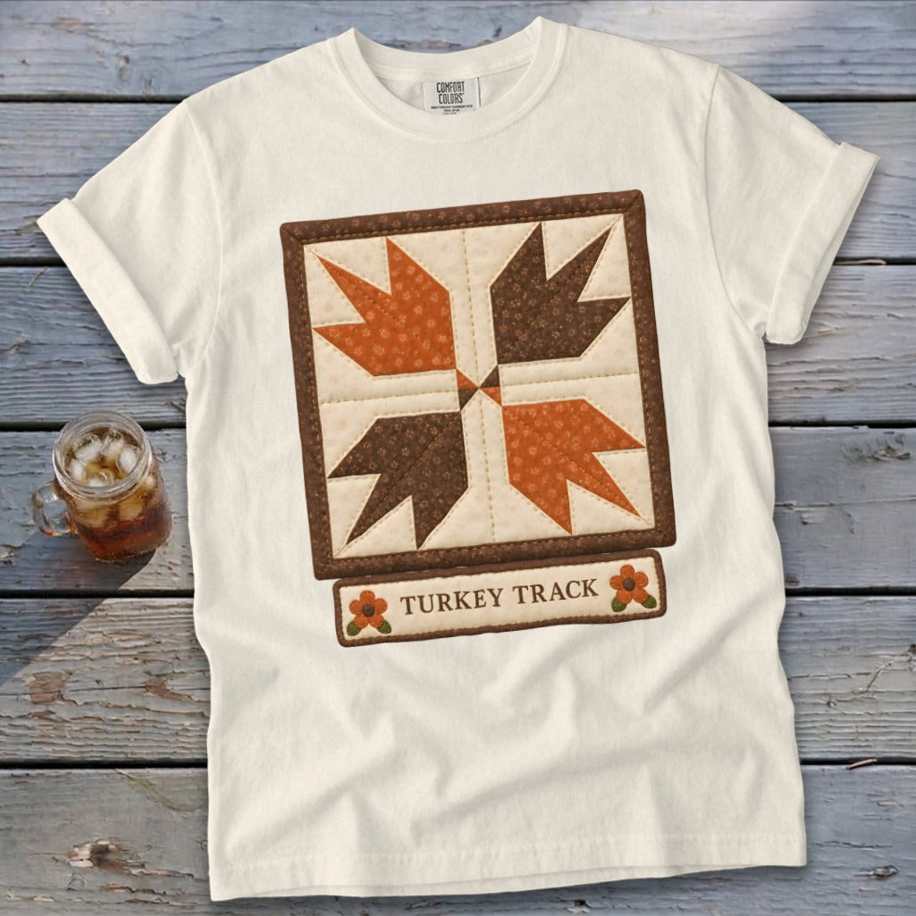 White t-shirt with a quilted "Turkey Track" design and floral accents.