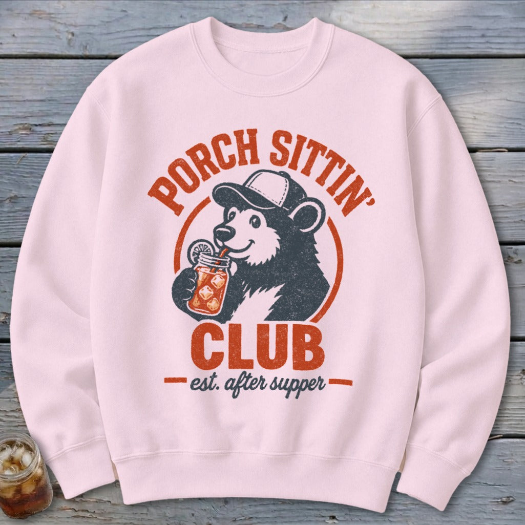 Pink crewneck sweatshirt with bear drinking from jar, "Porch Sittin' Club" text.