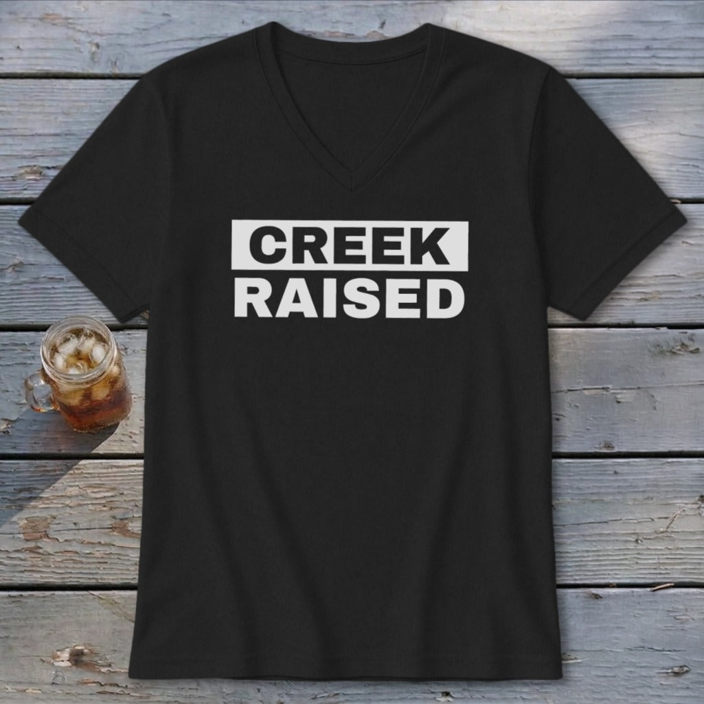 Black V-neck t-shirt with white text "CREEK RAISED" in a rectangle.