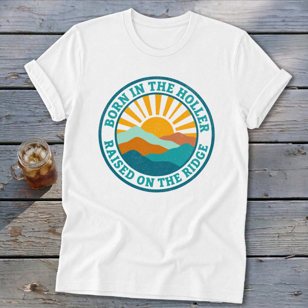 White t-shirt with a round graphic showing mountains, a rising sun, and text.